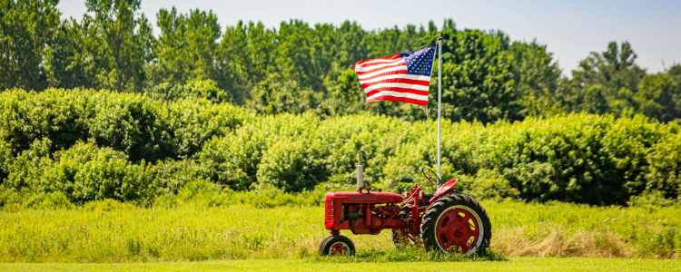 Red tractor with an American flag in a field.